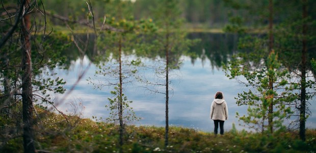 Ensam kvinna vid en sjö i skogen. Foto: Matilda Holmqvist